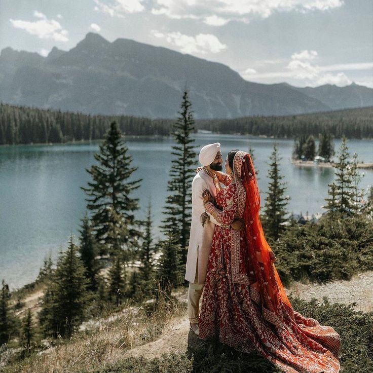 Kabir and Tara standing on a hillside overlooking a majestic mountain lake