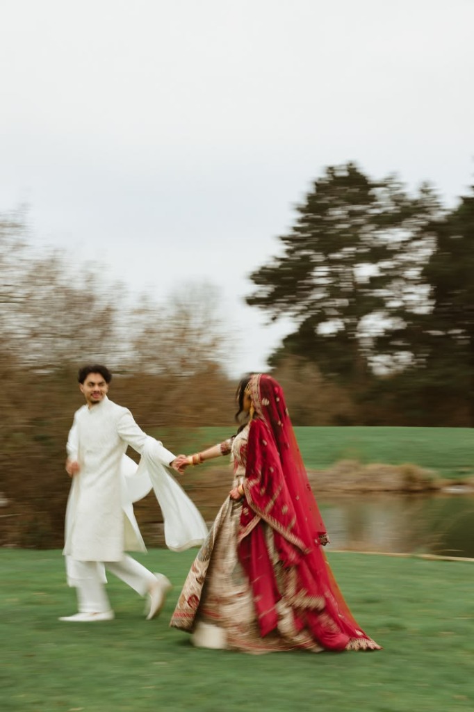 Timeless Gestures - Indian couple running hand-in-hand through a lakeside field